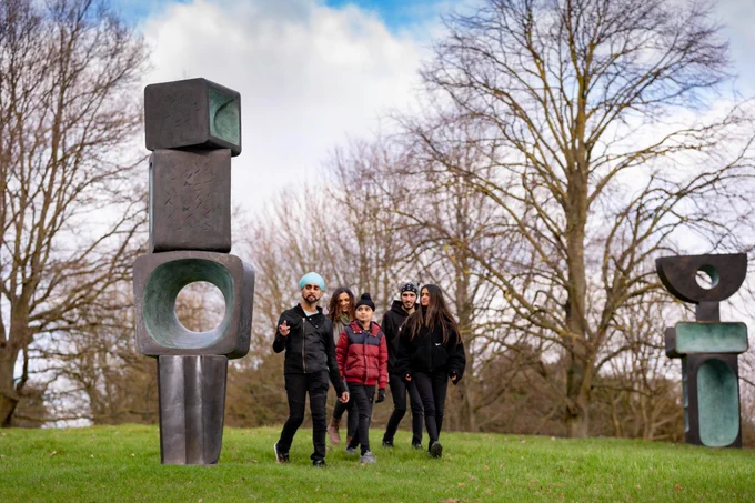 Visitors enjoying Barbara Hepworth's The Family Man, 1970 at Yorkshire Sculpture Park. Credit Jonty Wilde. 