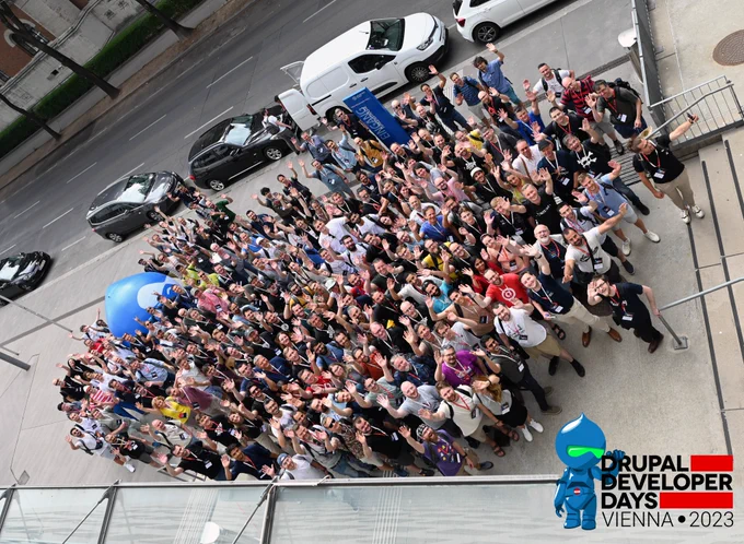 A bis group of Drupal enthusiasts waving at the camera.
