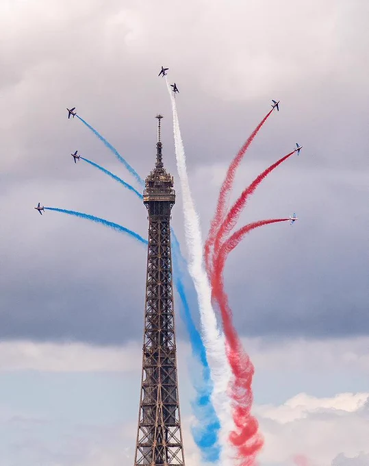 le haut de la tour eiffel avec les fumées bleu blanc et rouge