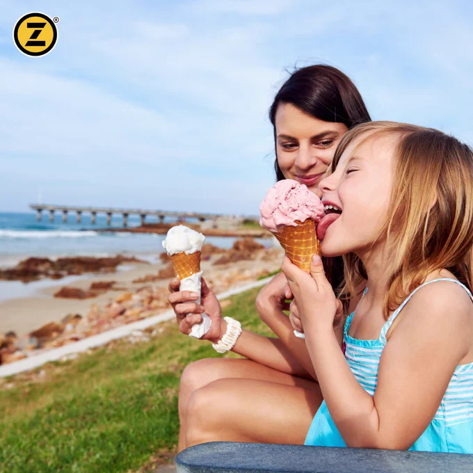 Mom and daughter licking ice cream cones at the beach. 