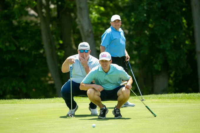 Golfers looking down the green to line up the shot.