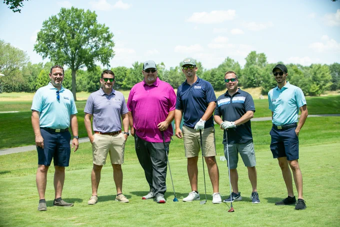A group of golfers pose for the camera.
