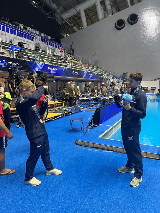 Jack Laugher gets a picture of Anthony Harding with his medal on poolside at the World Championships in Fukuoka