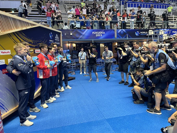 A crowd of photographers taking pictures of the Men’s 3m Synchro medallists