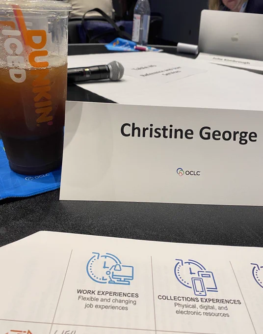 Dunkin Donuts ice coffee next to a white table tent that says Christine George in black type over a worksheet