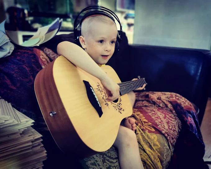 Child with cancer playing their Taylor swift guitar