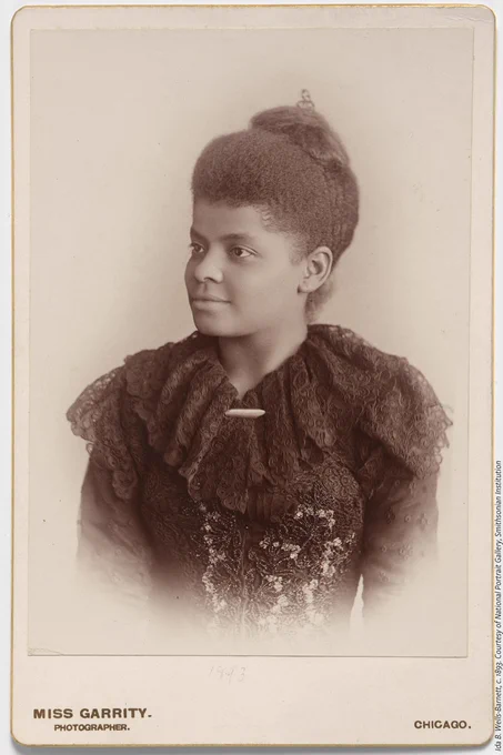 A black and white photo of Ida B. Wells wearing a black lace dress. 
