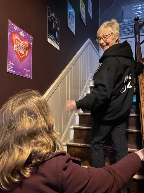 A Theatre@41 volunteer shows an audience member up the stairs to the theatre