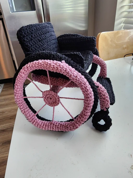 A side view of a black and pink crochet wheelchair