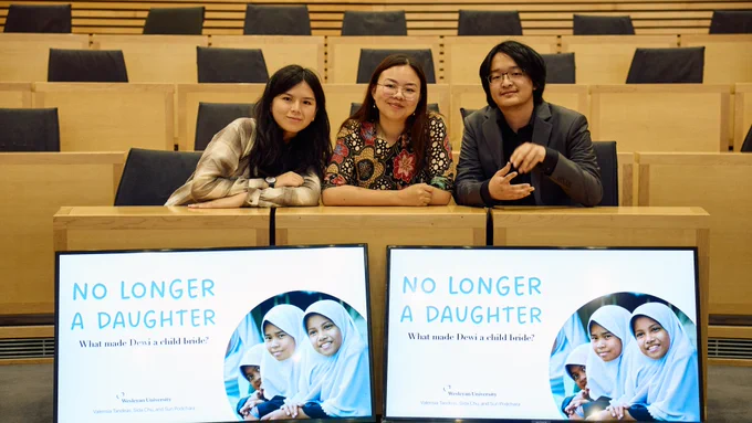 Valensia Tandeas, Sida Chu, & Podchara Boonbhati sat in front of their presentation, smiling.