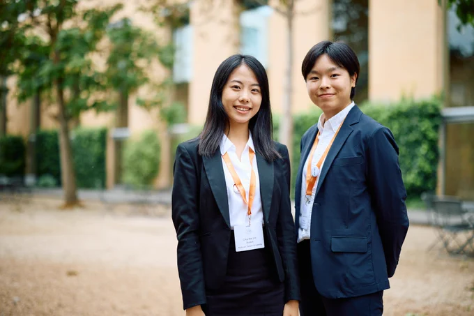 Yu-Chun Lin & Chia-Wei Lin standing in the school's courtyard smiling.