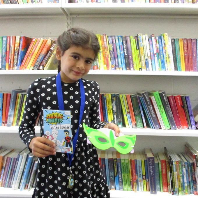 girl holding Reading Heroes leaflet and superhero mask