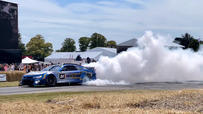 NASCAR Garage 56 spinning tyres in the Goodwood hill track. Lots of white tyre smoke behind.