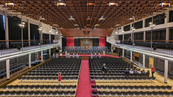 Photo of Lancaster University's Great Hall filled with chairs and people prepping for the graduation ceremonies 