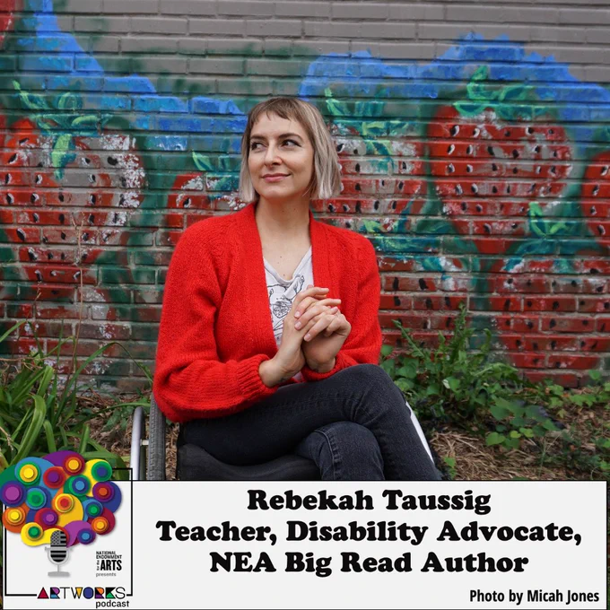 Rebekah Taussig, who is a white woman with bobbed hair. She is wearing a red sweater and sitting in her wheelchair in front of a wall painted with giant strawberries