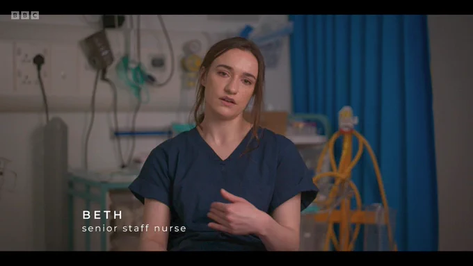 Beth is talking to the camera. There is medical equipment behind her.