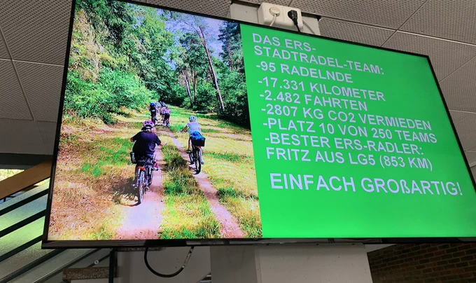 Auf dem Bildschirm im Foyer stehen die Ergebnisse des Stadtradelns und das Bild einer ERS-Fahrradtour.