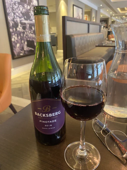 A bottle of red wine next to a glass with a glass of red wine next to it