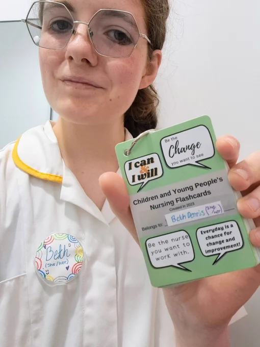 A selfie of me holding the student nurse cards in my uniform. 