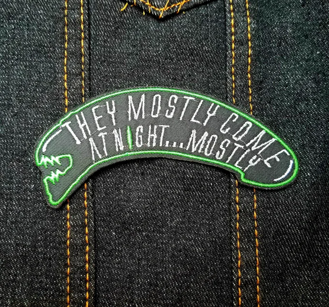 Alien head shaped embroidered patch that says they mostly come at night. Mostly.