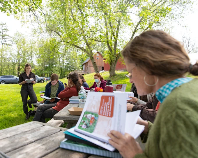 A farmer looks over a farm to school resource book outdoors at a picnic table during a workshop.