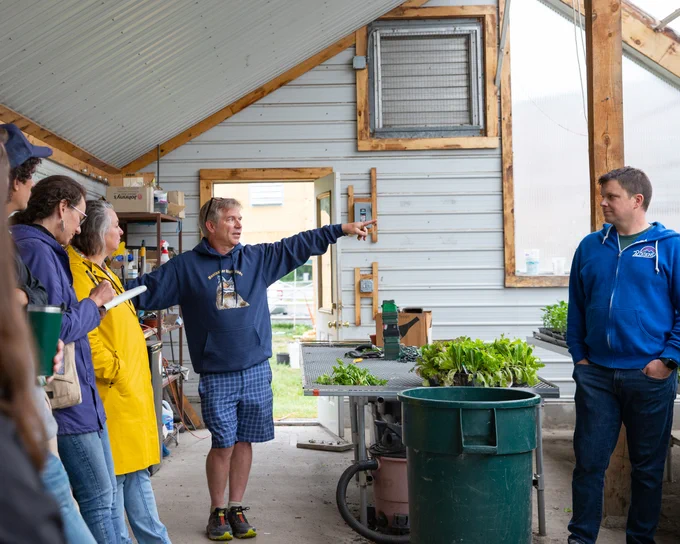 A group of educators gather in the school greenhouse at Montpelier High School.