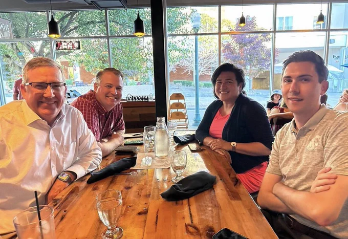 Four individuals sit around a rectangular table in a restaurant. President Schulz is pictured on the front left side and Sen. Randall is pictured on the back right side.