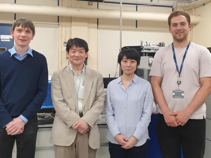 Dr Chris Wedge, Prof Akio Kawai, Dr Hirona Takahashi and Mr Dan Selby pictured in a laboratory in front of a benchtop NMR instrument 