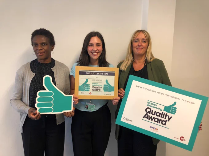 Photo of 3 YCC staff with framed certificate and 'thumbs up' quality award logo.