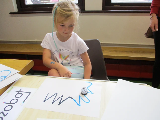 girl looking at robot on table