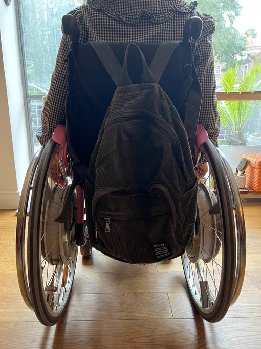 katie’s wheelchair from the back, with a rucksack hanging from the handlebars