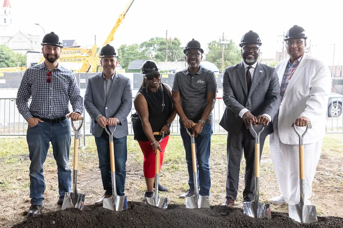 Photo ID: The mayor and a group of individuals hold onto shovels at a groundbreaking.