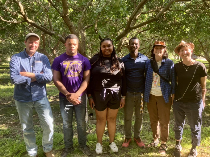 Three Black undergraduate students stand in an orchard with UC scientists at UC Kearney Agricultural Research and Extension Center.