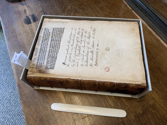 1524 copy of Erasmus’ “Paraphrases” resting in the lower tray of its soon-to-be new clamshell enclosure. The book is an old leather binding missing it’s front board, and the box tray is three-sided (open on the spine-side).