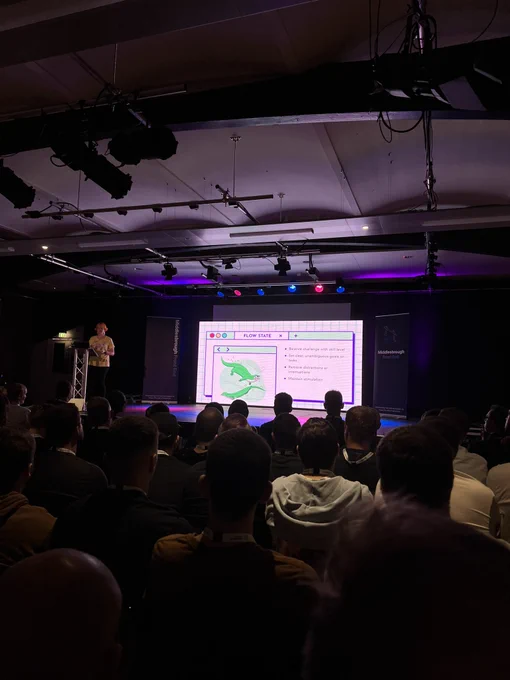 Jo Franchetti, the speaker, on stage showing a slide about “flow state”: balance challenge with skill level, set clear unambiguous goals or tasks, remove distractions or interruptions and maintain stimulation