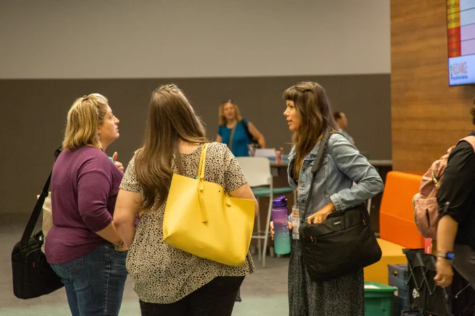 A group of three participants gather together and connect while deciding which breakout session to attend.