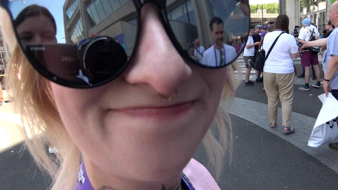 A close-up of Boba's face. In her sunglasses you can see the reflection of Sarah holding the camera and Lewis standing.