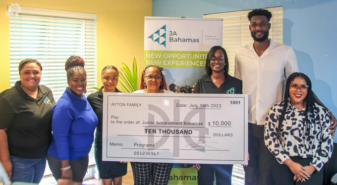 Deandre Ayton poses with a picture with members of Junior Achievement Bahamas with the $10K check pictured.