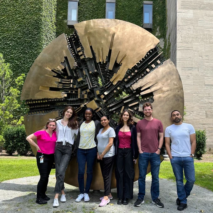 The Hayne Lab gathered in front of metal artwork sphere on campus