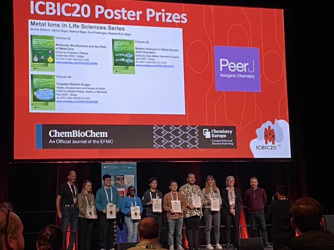 Young scientists on a stage holding poster prize awards