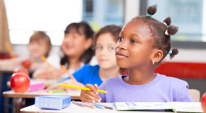 four elementary school students listening attentively in a classroom
