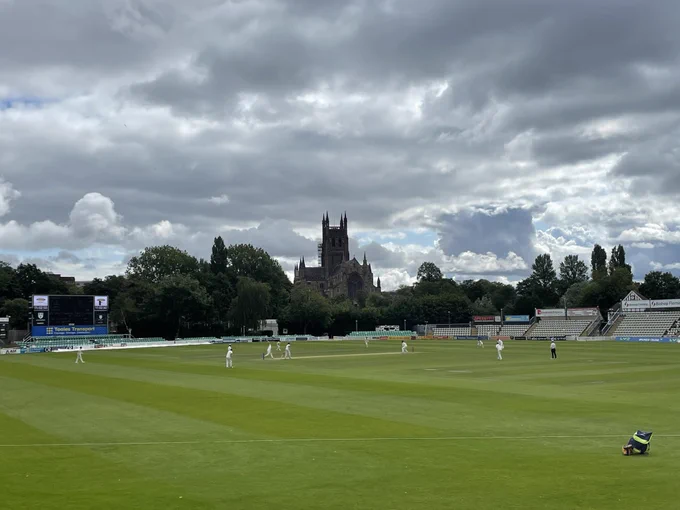View across the cricket ground with cricket players in the centre of the image and Worcester cathedral in the background