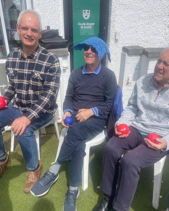 3 happy boccia players sat down ready to play