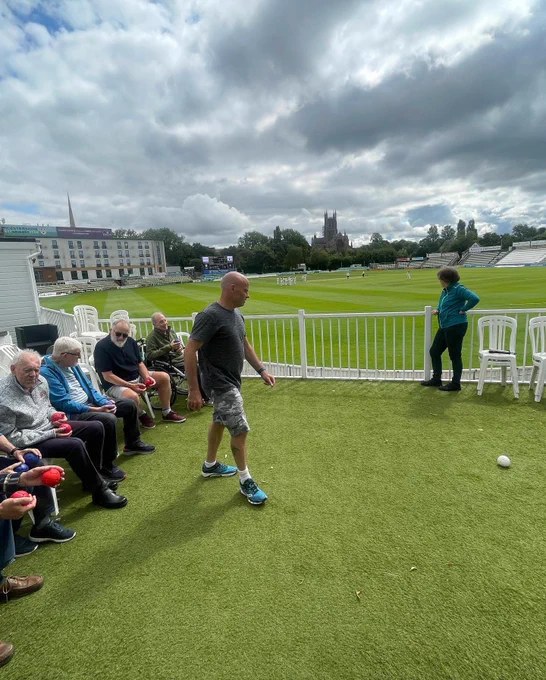 Group of people playing boccia on balcony looking over the cricket ground
