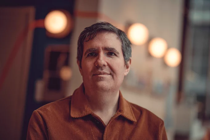 Image of new Royal Court artistic director David Byrne. He is wearing an orange corduroy shirt. 