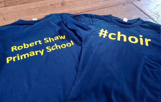 Two Robert Shaw Primary School blue t-shirts with #choir on the front in yellow 