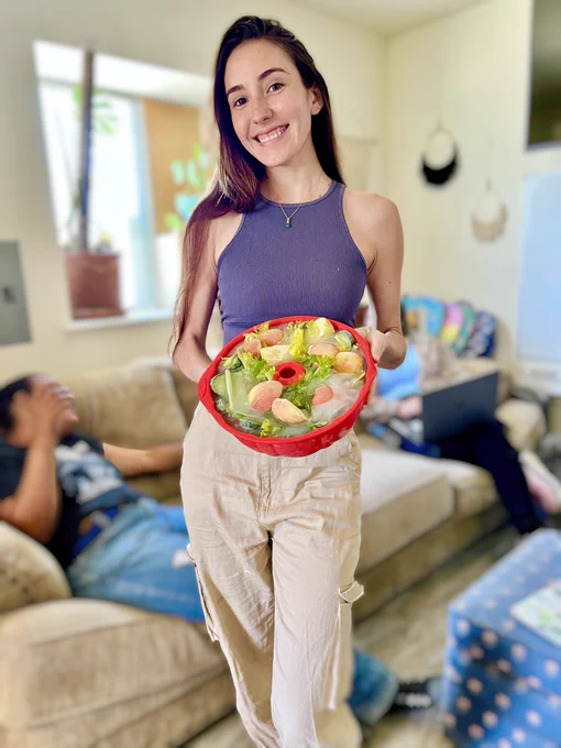 A photo of Nina, smiling, holding up her frozen salad donut
