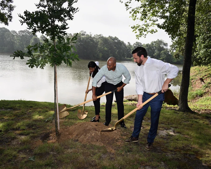 Photo of Governor Moore and Lt. Gov Aruna Miller shovel dirt to plant tree. 