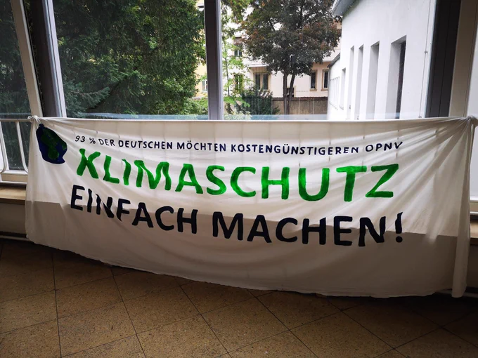 Ein Banner im Treppenhaus mit der Aufschrift: "93% der Deutschen möchten kostengünstigen ÖPNV.
KLIMASCHUTZ EINFACH MACHEN." 