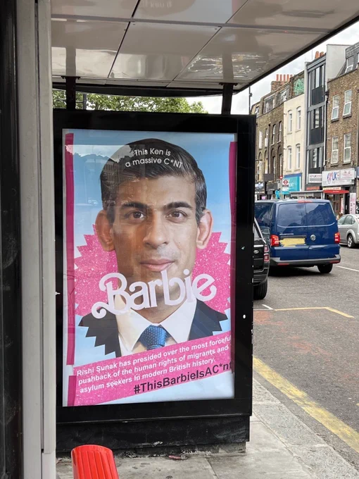 Picture of bus stop poster of mimicking Barbie movie marketing with Rishi Sunak. Text on poster reads “This Ken is a massive C*NT.” “Rishi Sunak has presided over the most forceful pushback of the human rights of migrants and asylum seekers in modern British history. #ThisBarbieIsAC*nt”